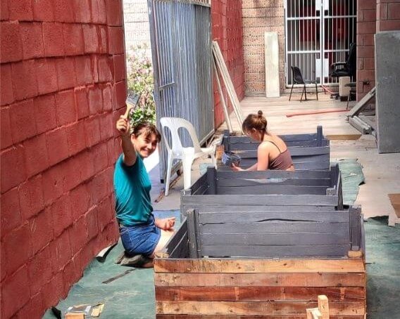 Two women painting crates